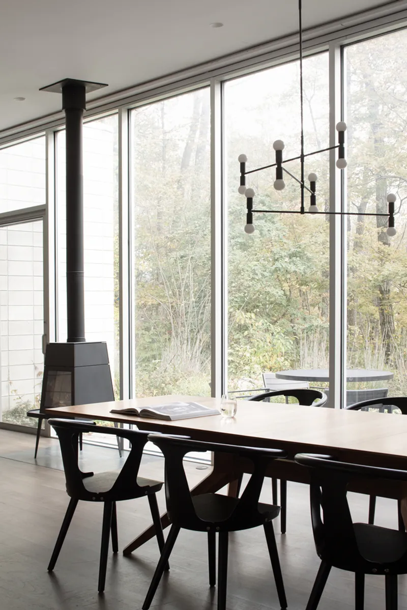 Dining area with floor-to-ceiling glazing and black multi-arm chandelier above the table