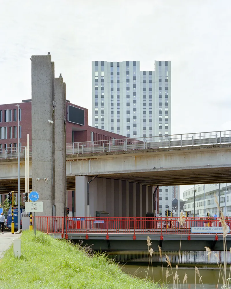 Concrete highway overpass with red barriers crossing a canal in front of the tower
