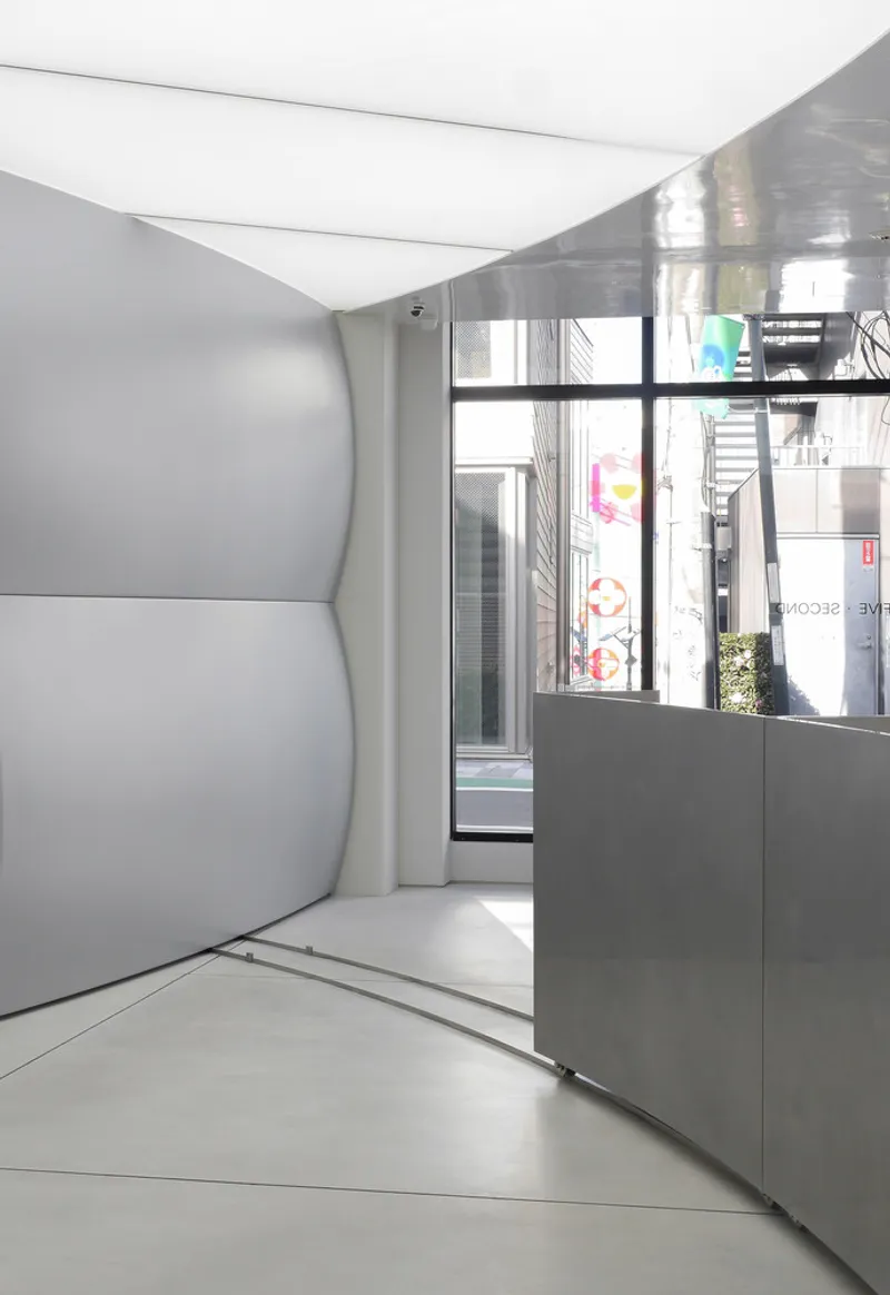 Curving corridor with white cove ceiling leading to glazed storefront with daylight