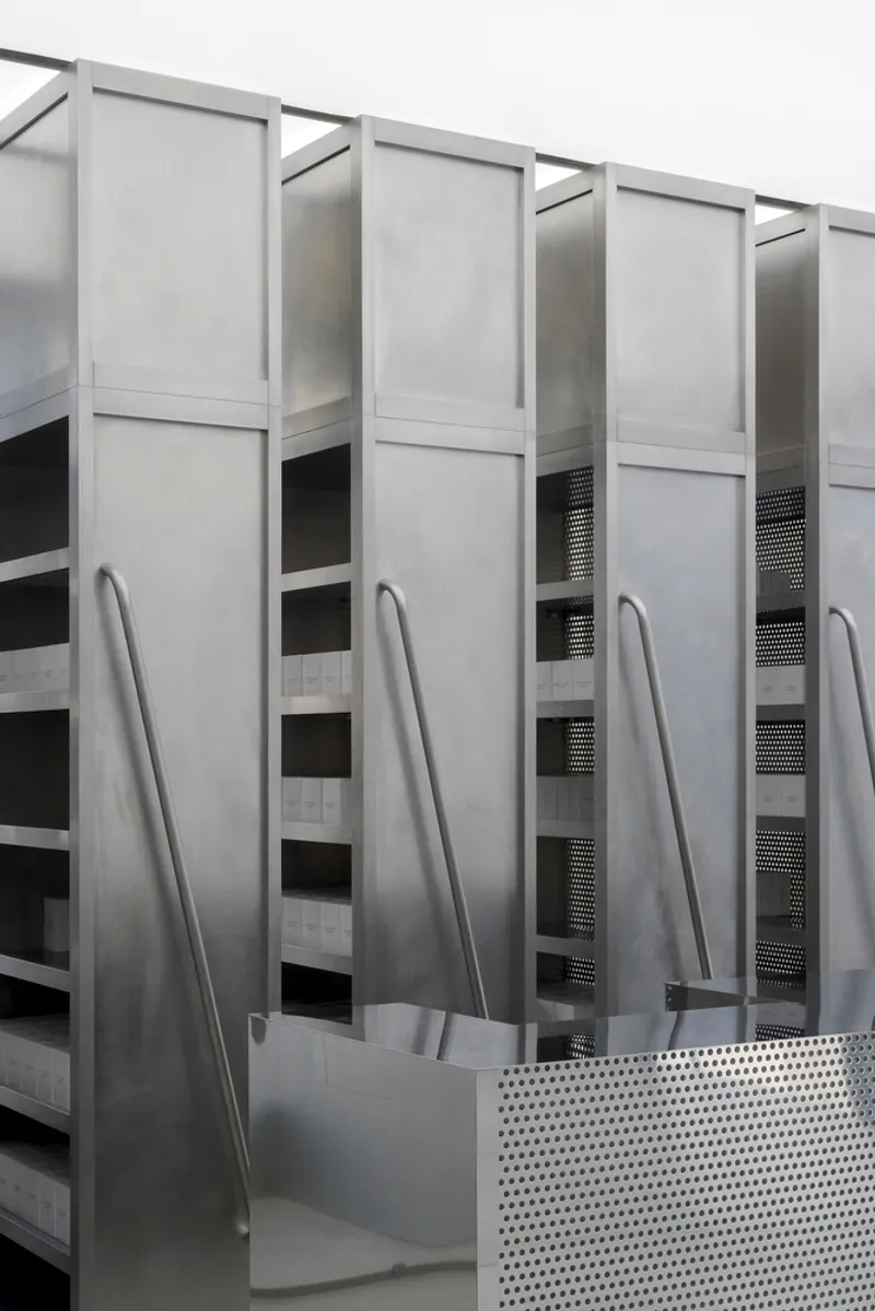 Close-up of vertical metal panels with diagonal handrails and perforated safety barrier