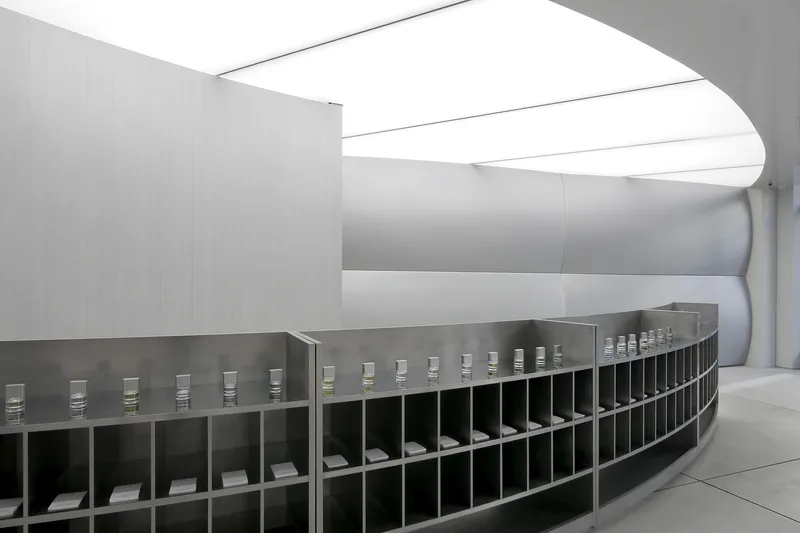 Long curving display counter with gridded compartments beneath continuous ceiling skylights