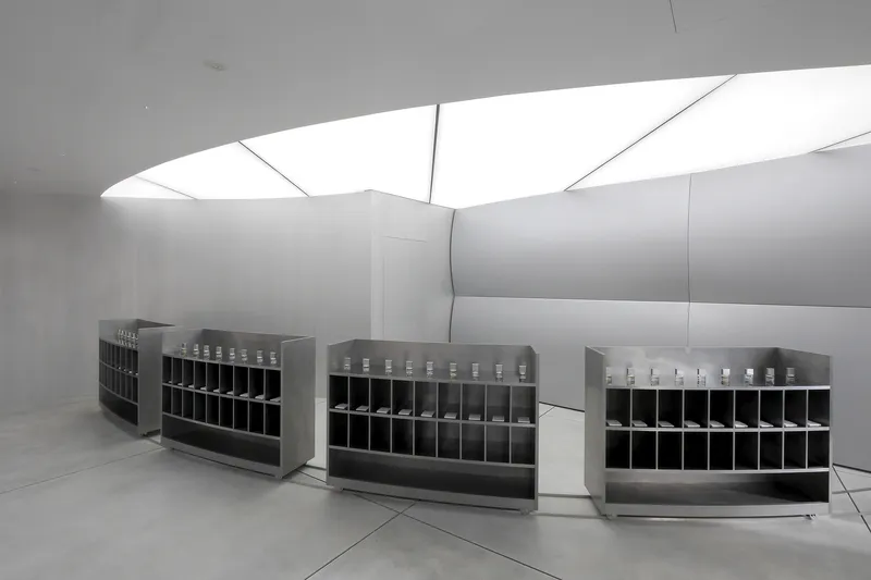 Interior gallery with metal shelving units below a folded skylight ceiling