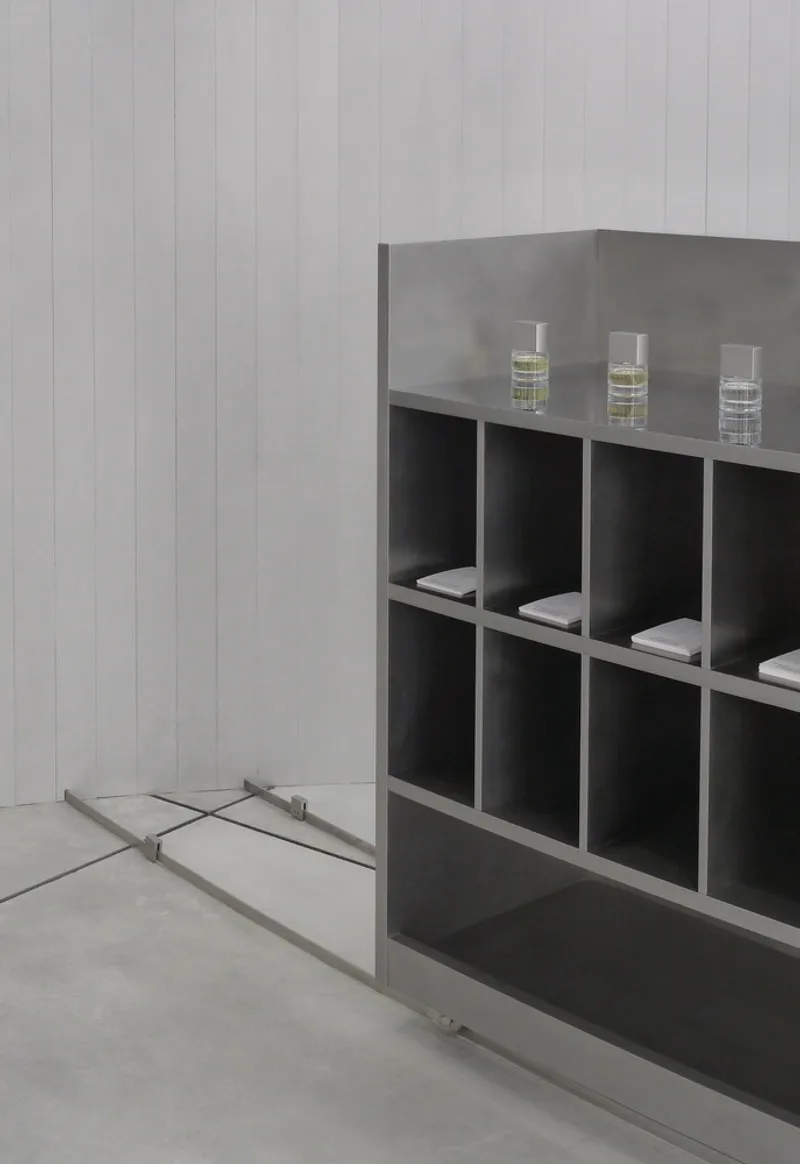 Close-up of metal shelving cubicles with glass vials against a paneled wall