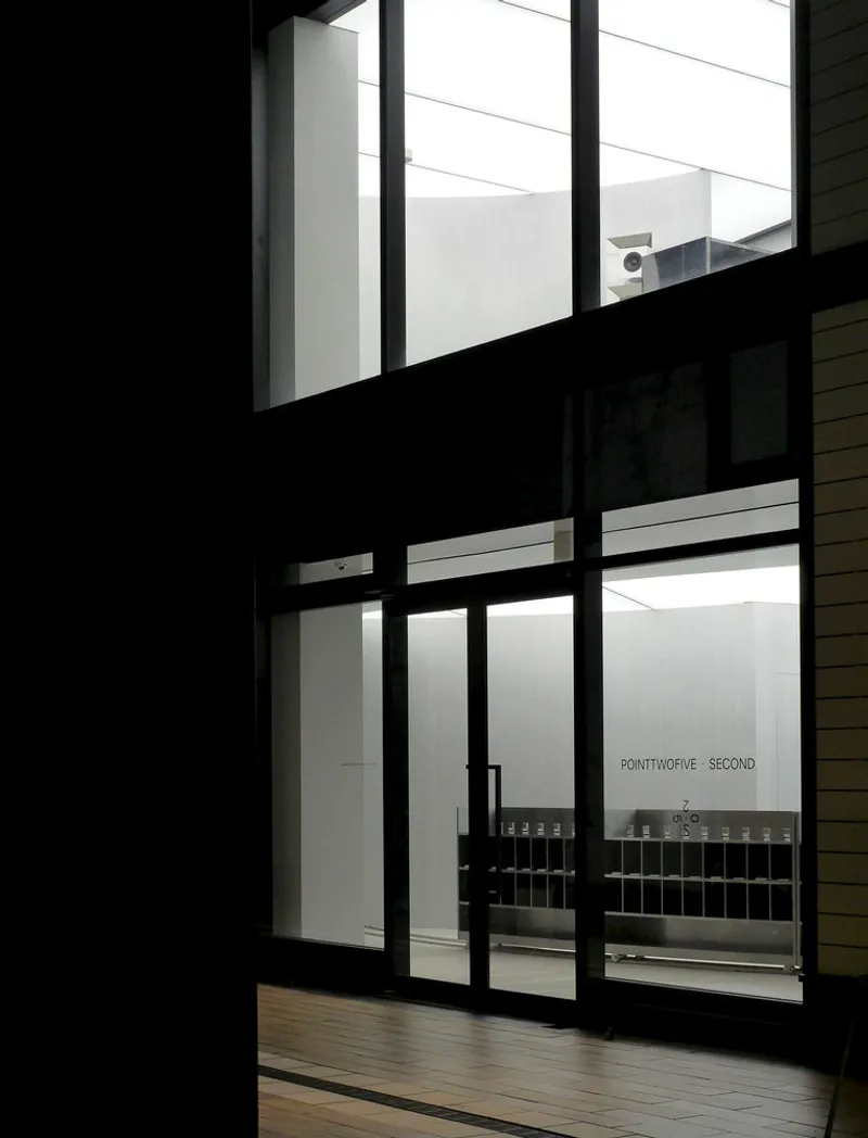 View through black-framed glazing into the illuminated interior at dusk