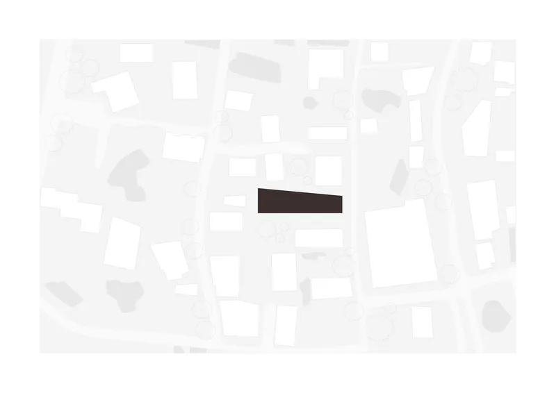Site plan drawing showing a rectangular volume positioned among surrounding urban blocks and street trees