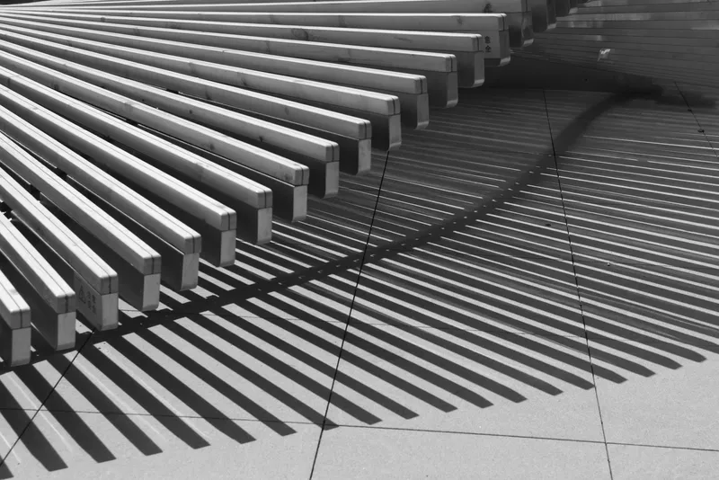 Detail of linear timber battens creating rhythmic shadow patterns on concrete pavers