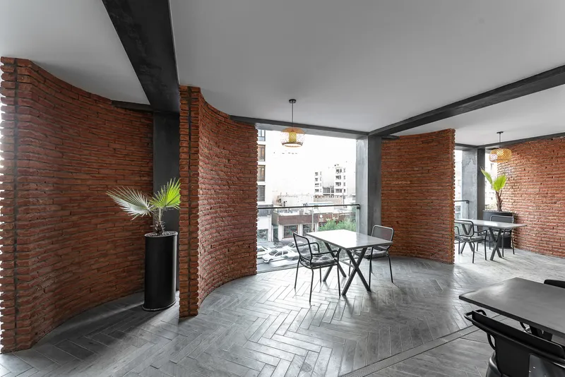 Terrace dining area with curved brick partitions and herringbone floor pattern opening to balcony