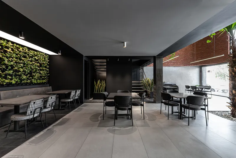 Dining room with vertical green wall and view through to the brick courtyard with palm tree