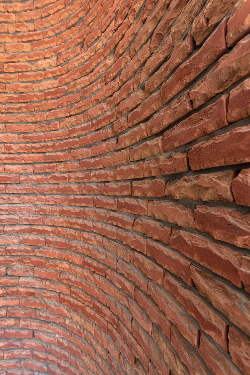 Curved brick wall detail showing undulating surface texture in natural daylight