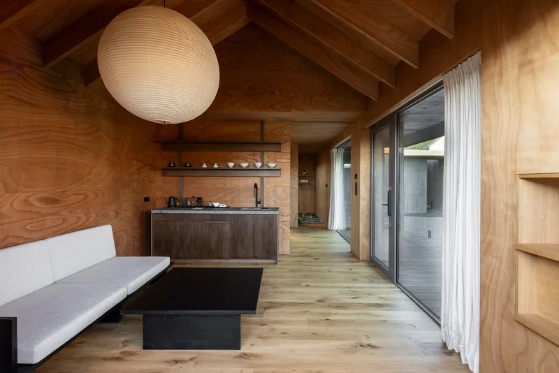 Interior living space with exposed timber ceiling rafters and plywood wall cladding throughout
