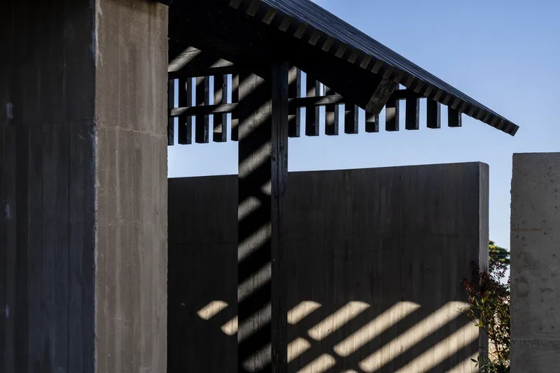Close-up of gabled eave detail with exposed rafters and shadow patterns cast across timber walls