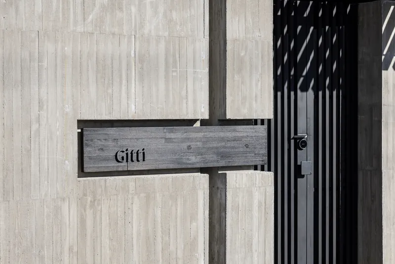 Painted timber mailbox attached to a vertical slatted screen beside a pale timber wall
