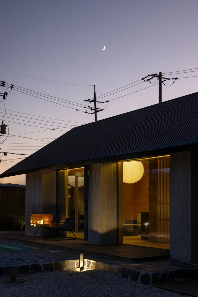 Glazed porch with glowing interior light and crescent moon overhead at dusk