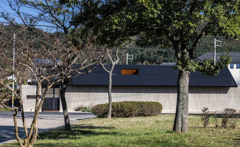 Street view of the concrete and corrugated metal facade with bare trees in the foreground