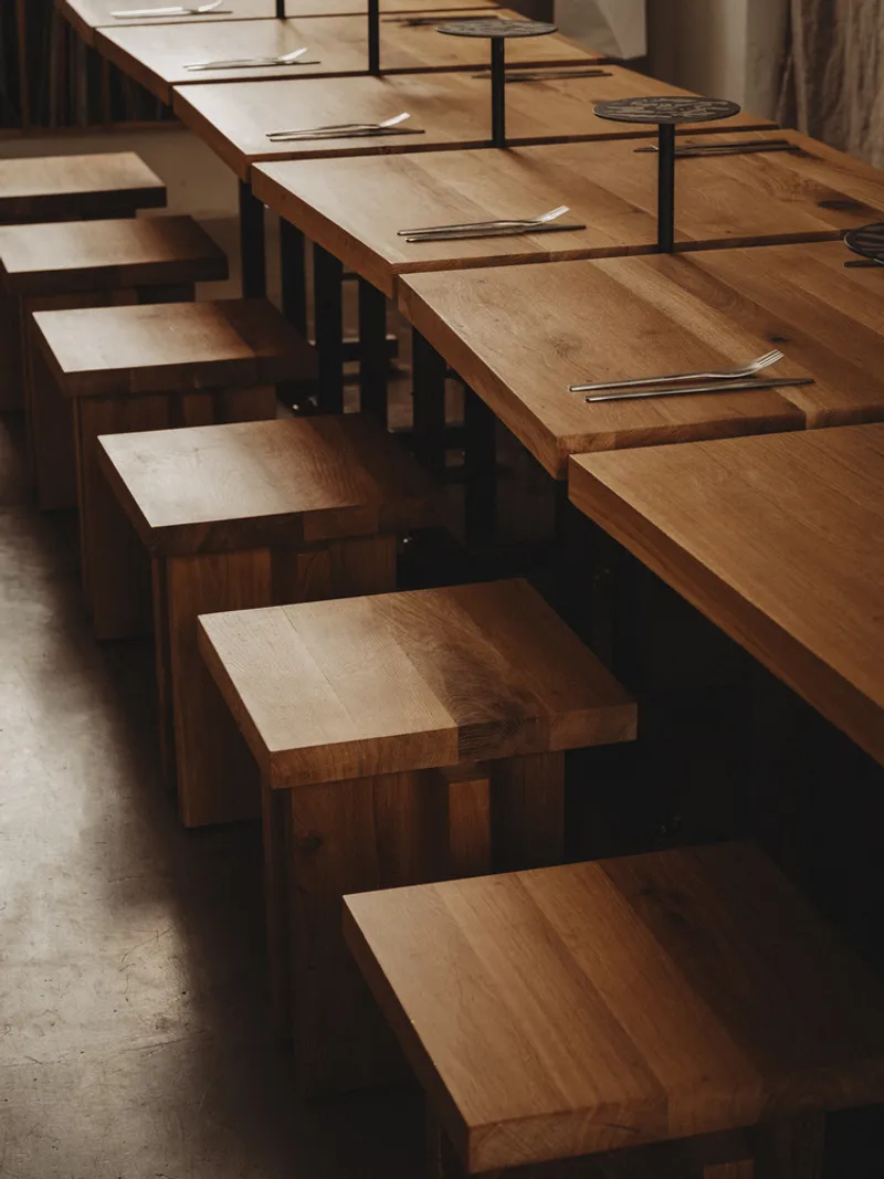 Angled view of the timber counter and block stools with place settings