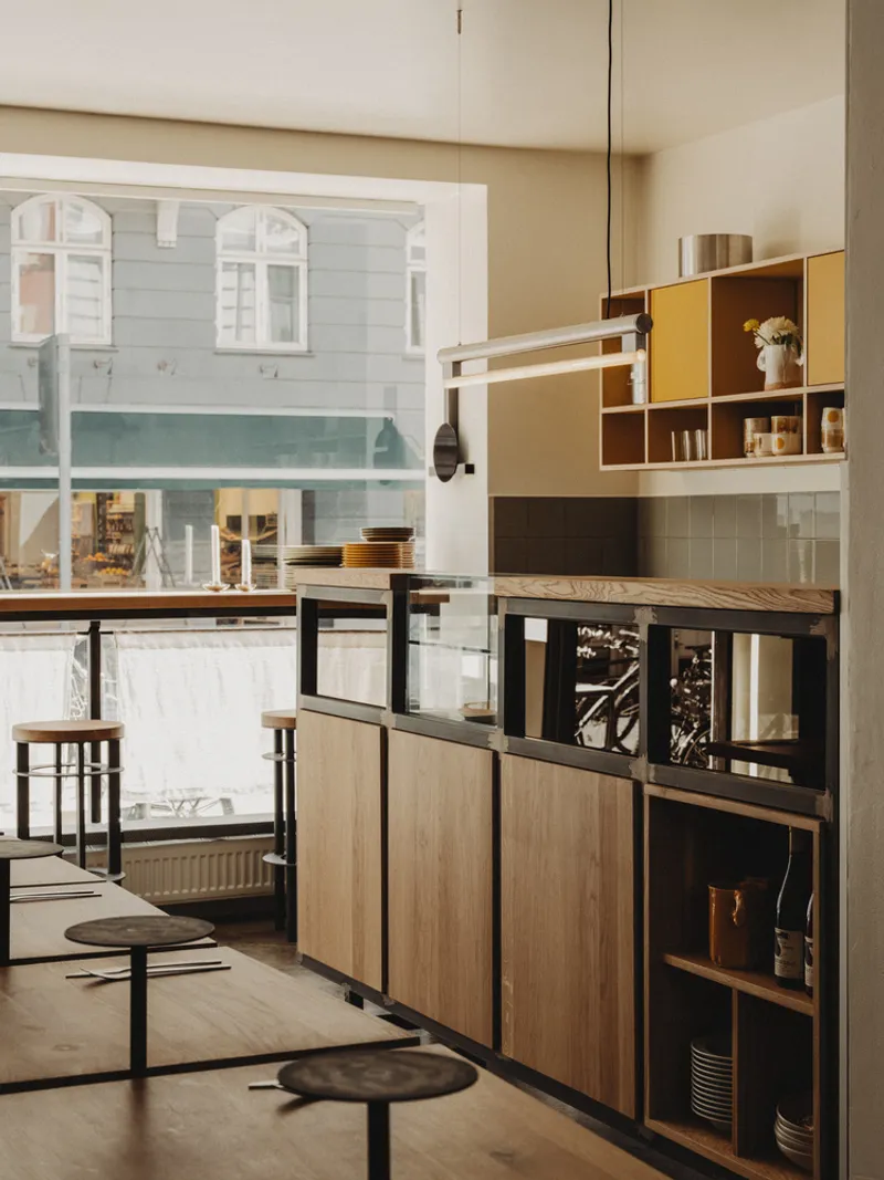 Open kitchen shelving with wood and yellow panels next to a large street-facing window