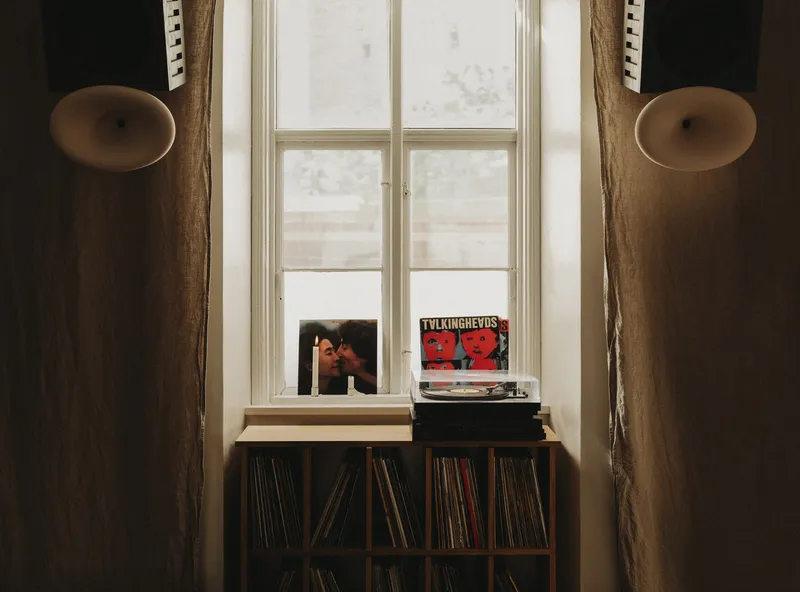 Vinyl record storage below a window sill with albums propped against the glass