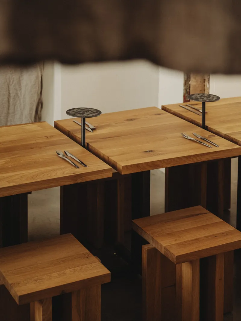Detail of timber tabletops with metal risers and chopsticks arranged for service