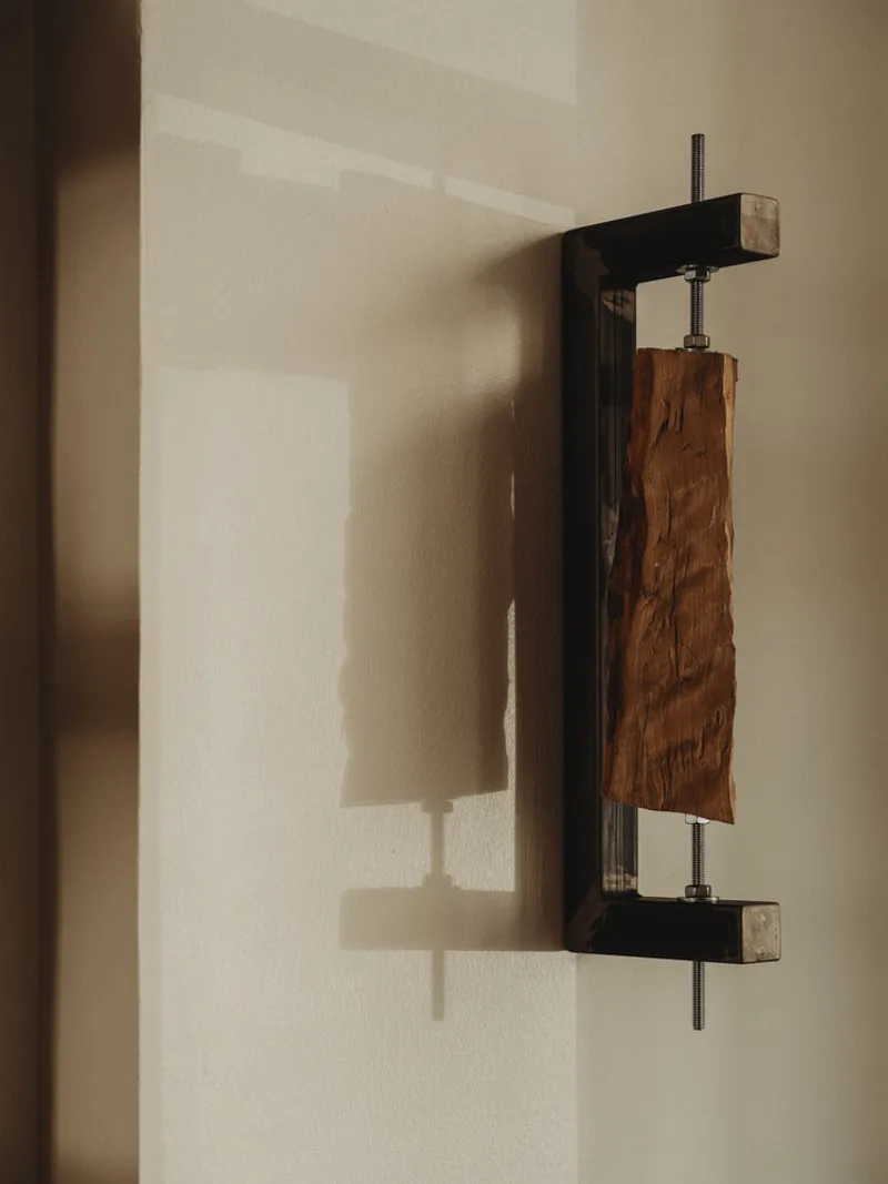 Wall-mounted wooden sconce with tensioned fabric panel between metal and timber frames
