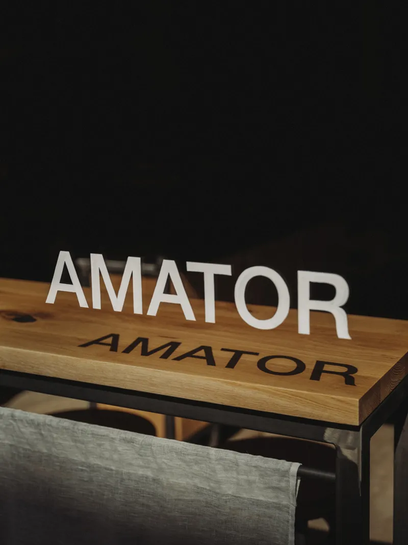 Timber bench with engraved lettering beneath white dimensional letters against a dark backdrop