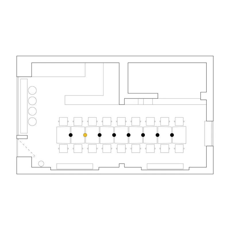 Floor plan drawing showing a rectangular dining space with central communal table and perimeter service areas