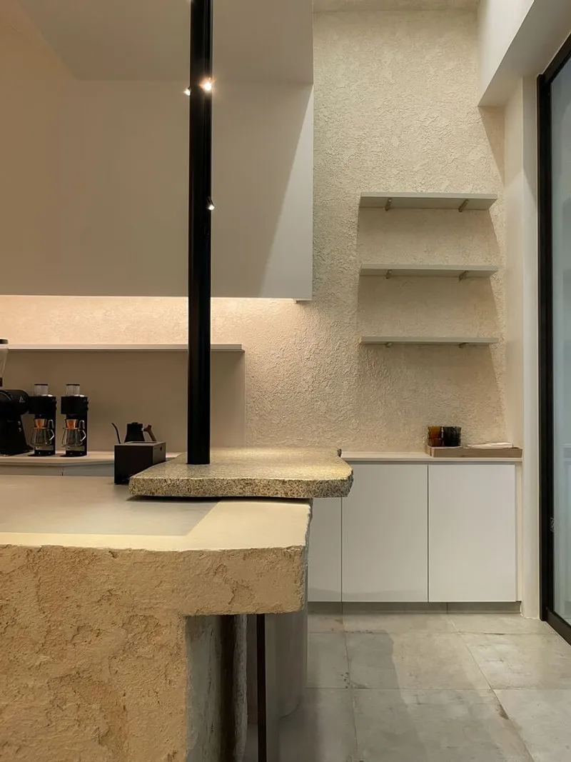 Corner detail showing floating shelves on textured plaster wall beside terrazzo counter edge