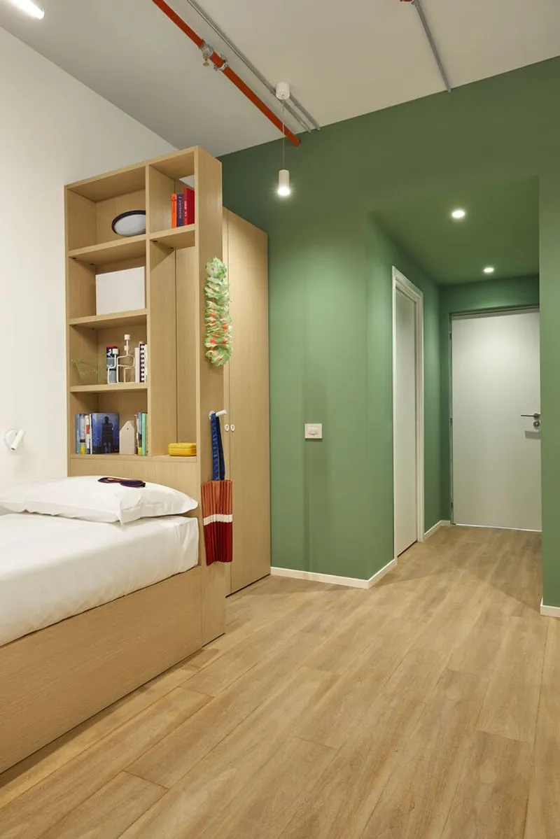 Compact bedroom with sage green walls and white door framed by blonde wood platform bed