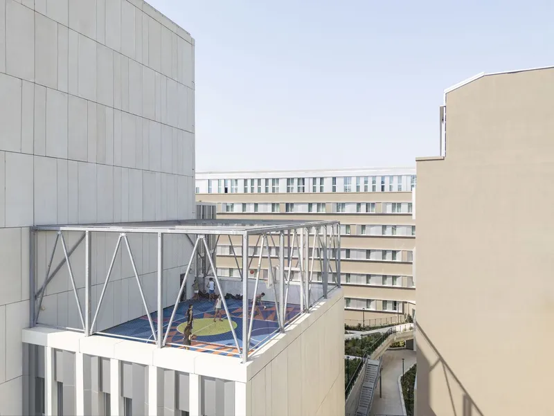 Elevated view of the white steel framed rooftop court perched between residential blocks under overcast sky