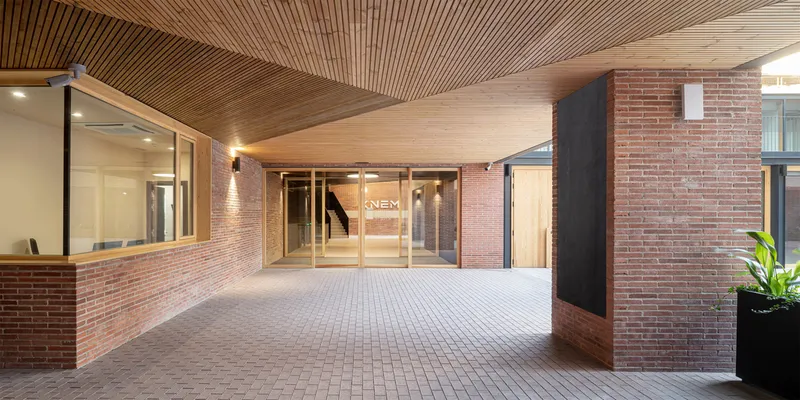 Covered entry portico with exposed timber slat ceiling and red brick walls at dusk