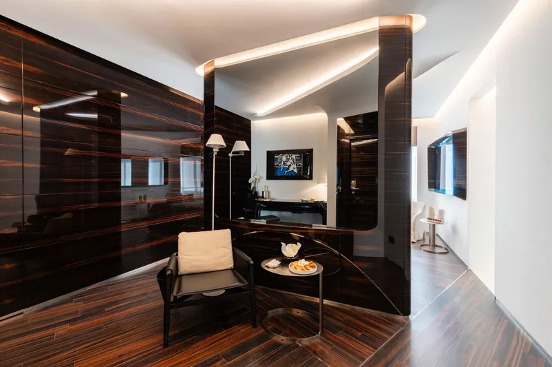 Lounge area with glossy striped wood paneling and floating ceiling planes with concealed lighting