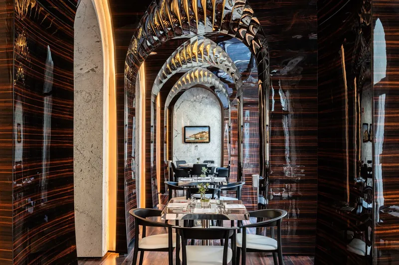 Dining room with striped wood paneling and backlit concrete columns framing arched openings