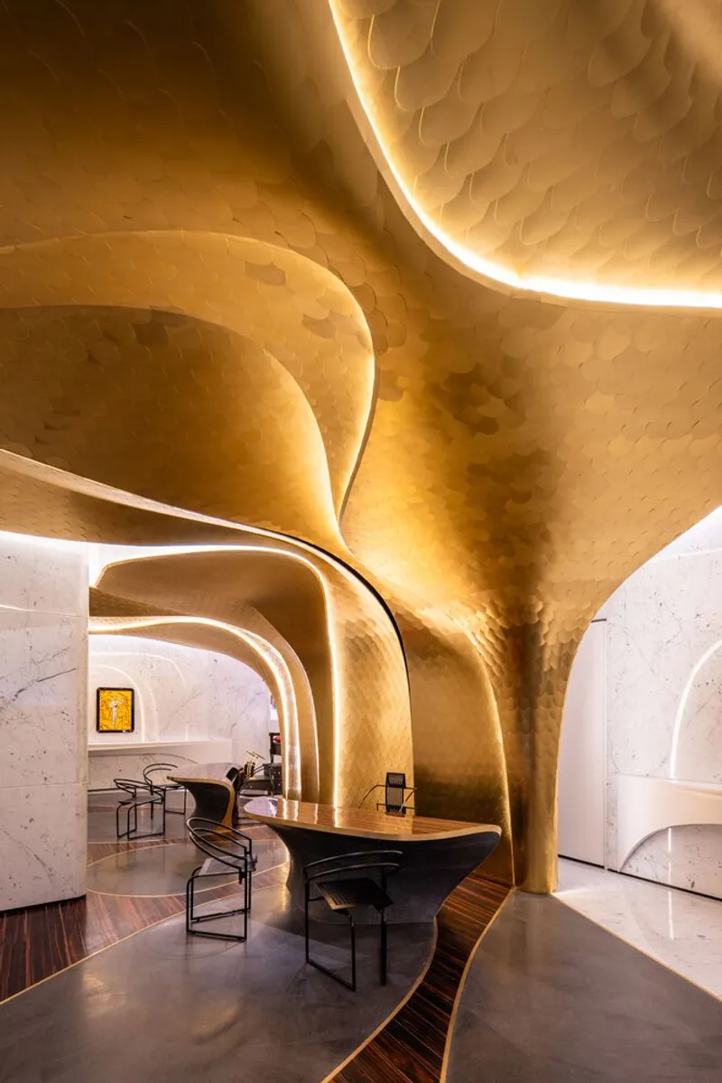 Interior view of sculpted gold ceiling with branching forms and integrated lighting over dining tables
