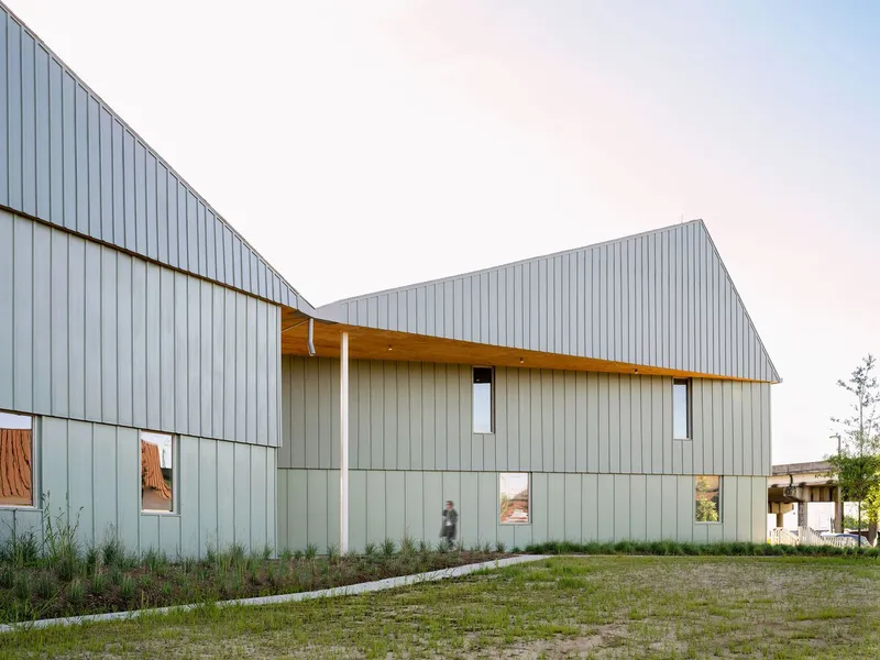 Two gabled volumes clad in vertical metal panels with punched windows and a connecting breezeway
