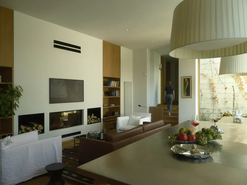 Living area with recessed fireplace and figure ascending timber stair in background