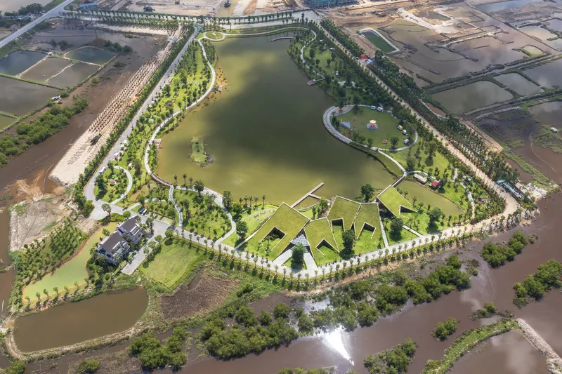 Drone view of the angular green roofs arranged around a central lake and tree-lined paths