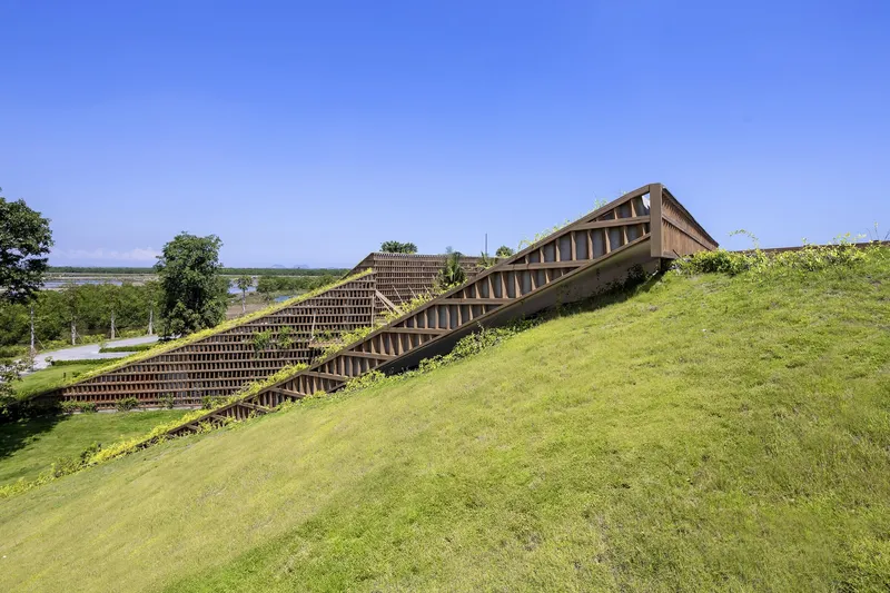 Angled view of the grass-covered roof plane rising above the gridded timber brick wall