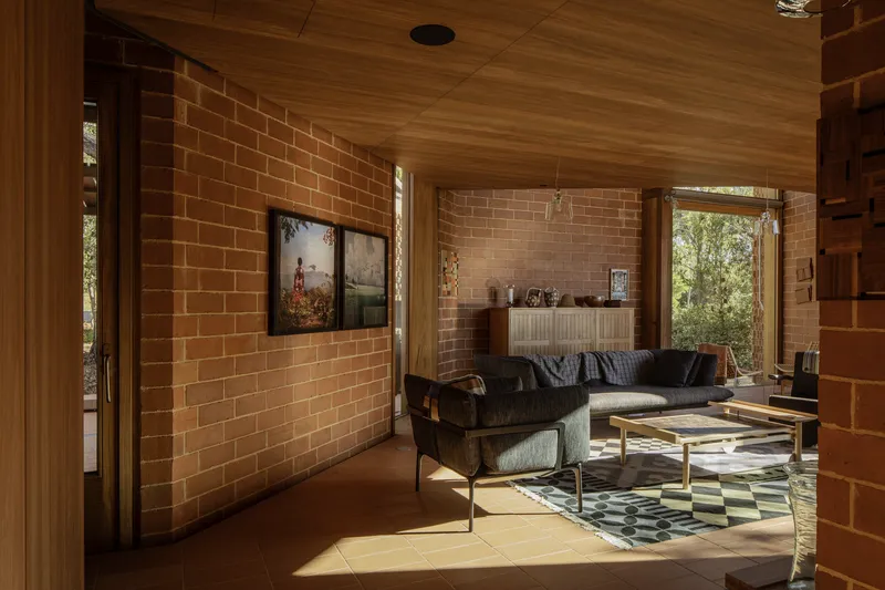 Living room with exposed brick walls and timber ceiling bathed in afternoon sunlight from open doorways