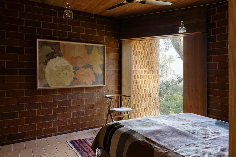 Bedroom with brick walls and a textured screen door opening to the garden at dusk