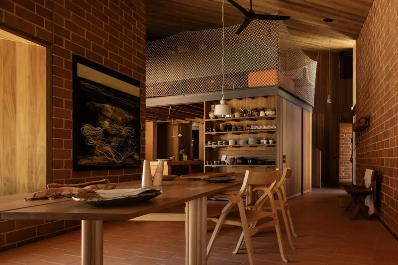 Kitchen with mesh-wrapped volume and timber shelving beneath exposed wood plank ceiling