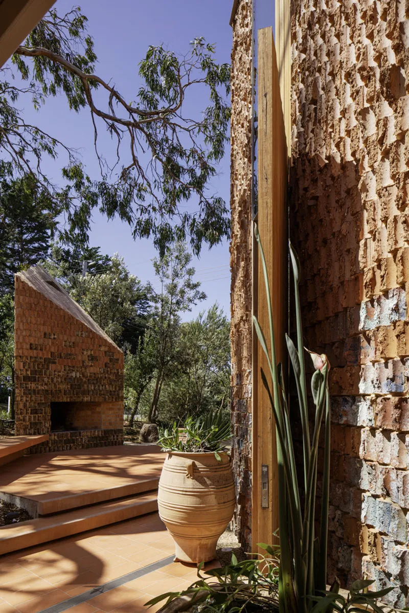 Detail of the textured brick wall corner with planted ceramic pot and overhanging tree branches