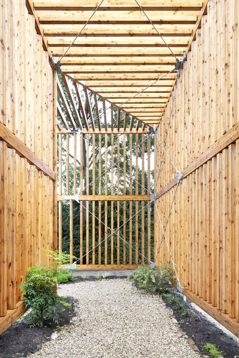 Timber pergola passage with exposed beams and vertical wood screen framing garden plantings