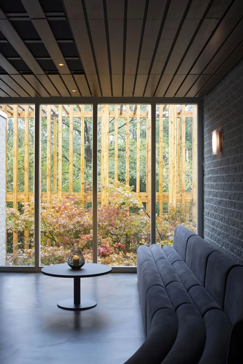 Window wall overlooking vertical timber slats and autumn foliage from a seating area