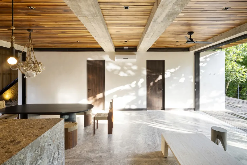 White plaster wall with dappled sunlight filtering through trees onto the polished concrete floor