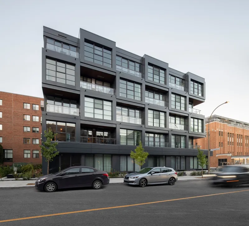 Street view of the gridded glass and metal facade with parked cars along the sidewalk