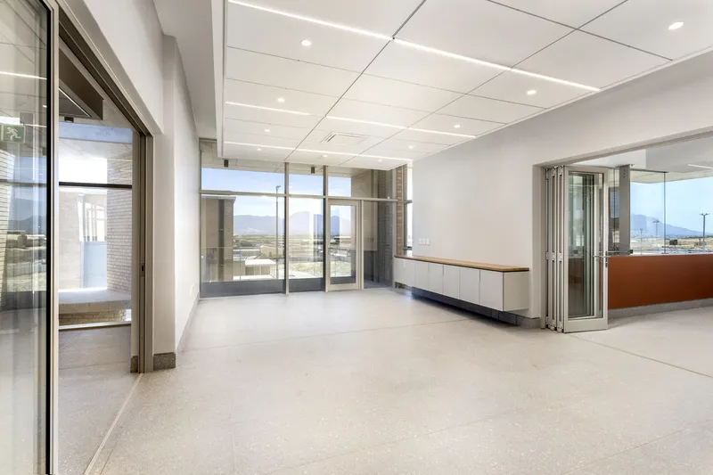 Interior room with white suspended ceiling, glass partitions and built-in casework overlooking distant mountains