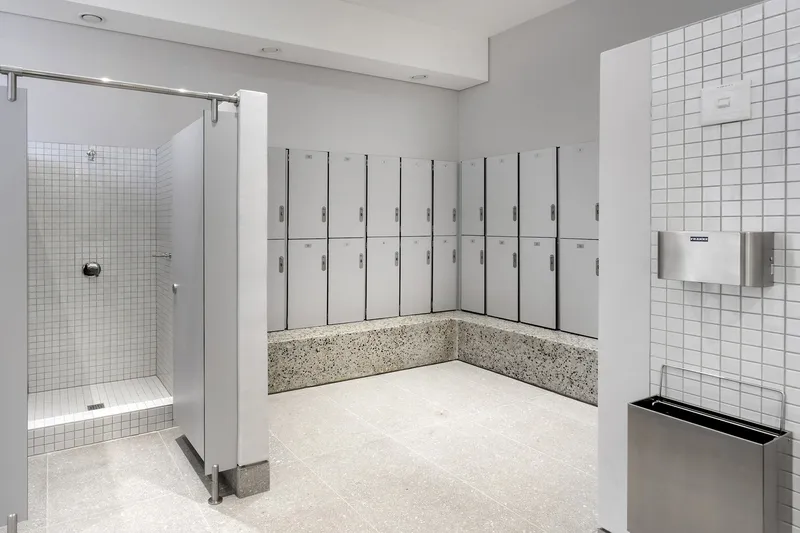 Locker room with white tile walls, terrazzo base and shower stall with glass partition