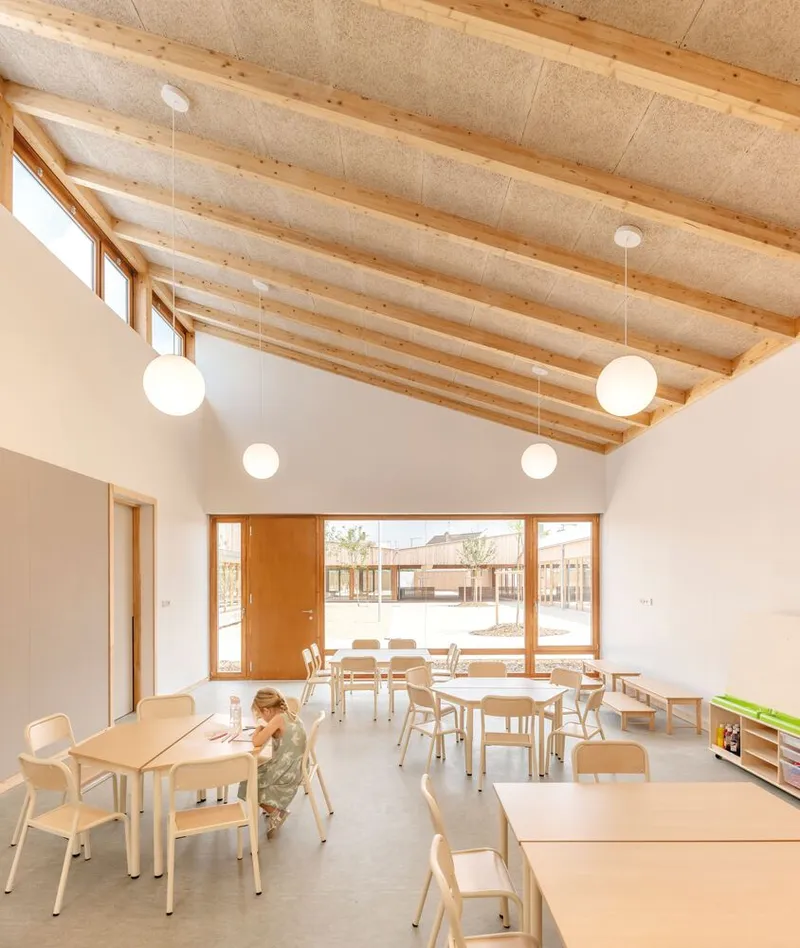Classroom interior with vaulted timber beam ceiling and globe pendant lights with a child seated