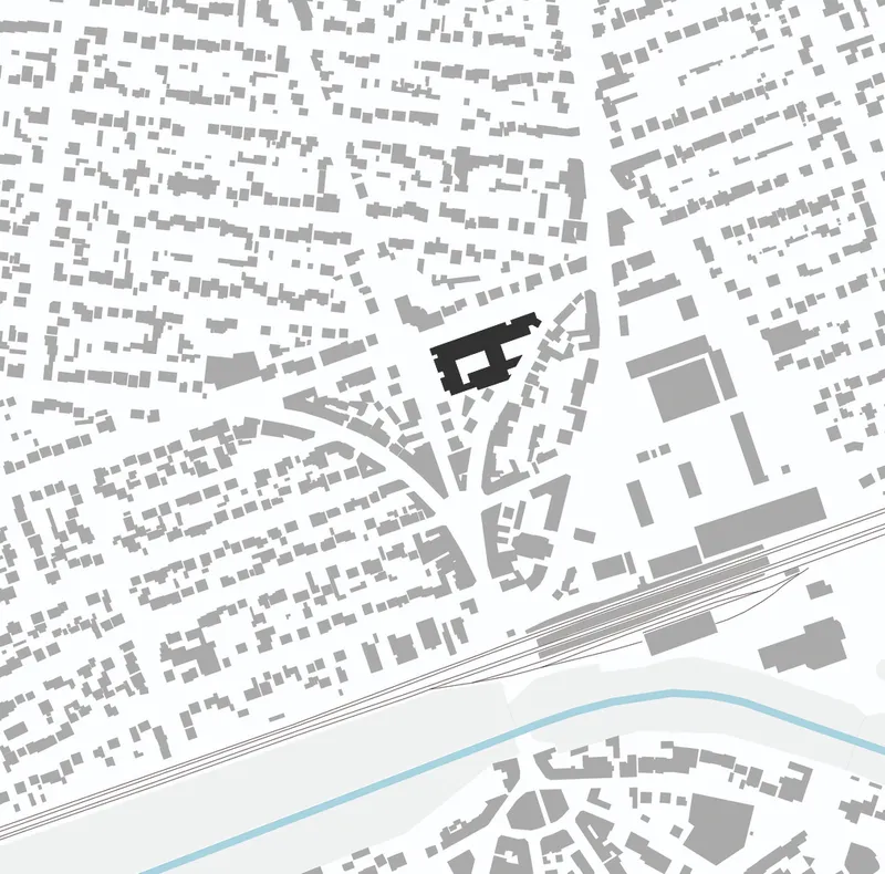 Site plan drawing showing the building footprint in black within a dense urban fabric and river
