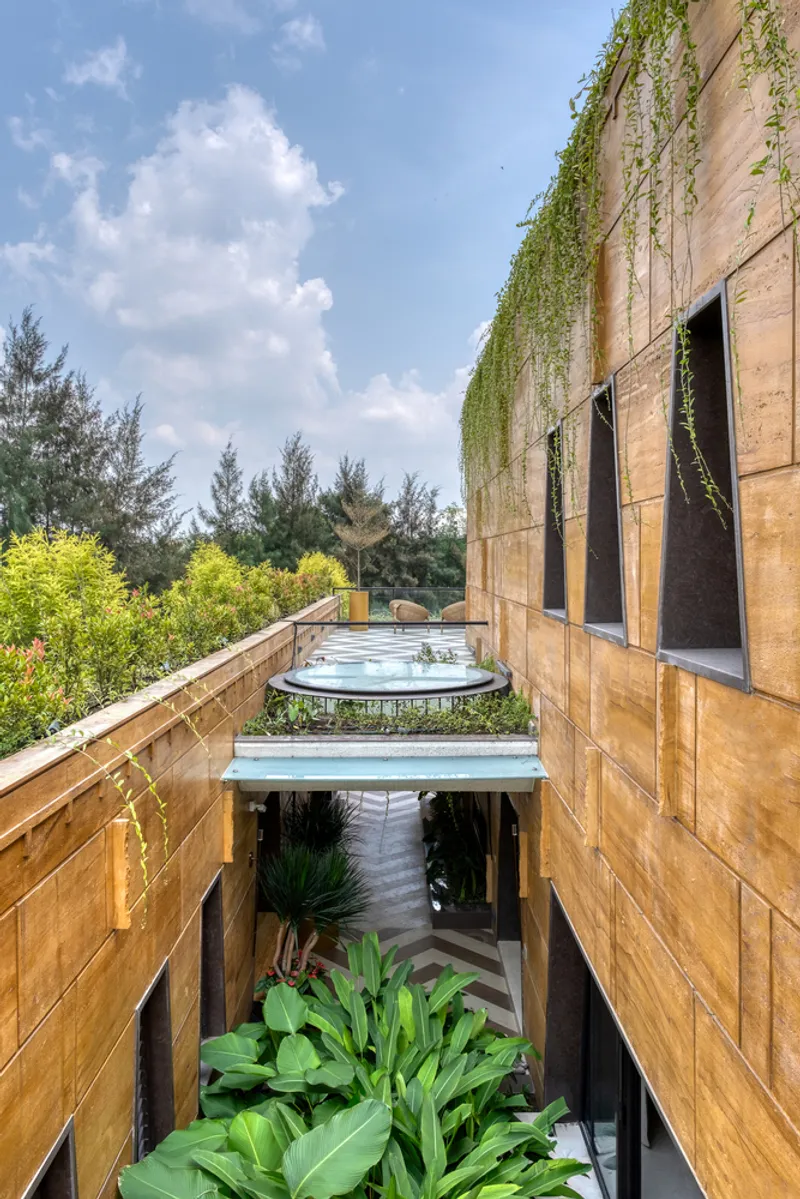 Interior courtyard with cascading greenery and circular skylight opening between sandstone walls