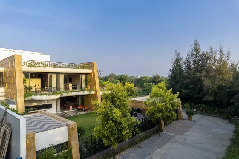 View across the garden terraces showing stone-clad volumes and planted roofs under afternoon light